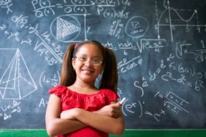 Student in front of blackboard with complex problem on board.